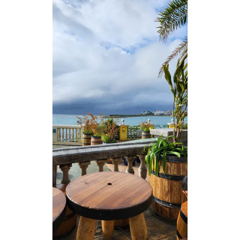 Terraza frente al mar con mesas de madera en American Village en Chatan, Okinawa
