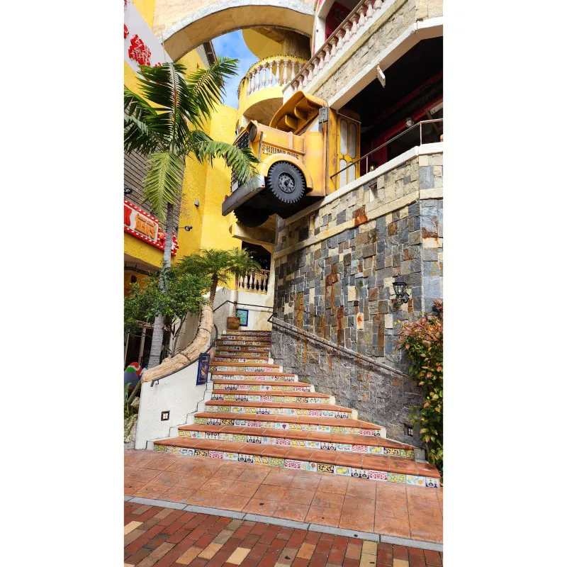 Instalación de un autobús amarillo sobre escaleras de azulejos en American Village en Chatan, Okinawa