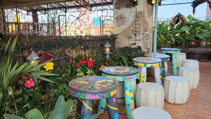 Asientos al aire libre con mesas pintadas de colores y plantas en American Village en Chatan, Okinawa