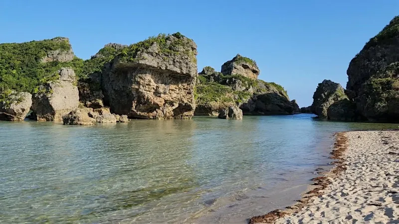 Playa de arena blanca con grandes formaciones rocosas en aguas azules y cristalinas en Hamahigajima